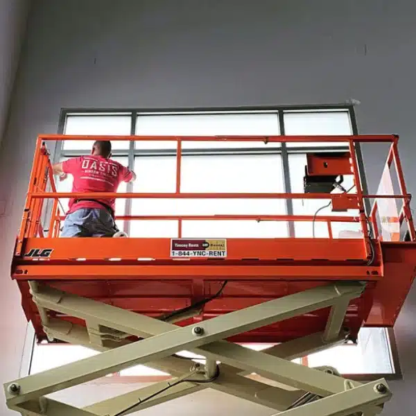 man on a mechanical scaffolding applying window tint